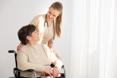smiling nurse supporting senior woman on a wheelchair