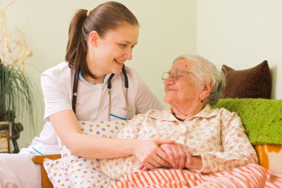 nurse and senior woman holding hands while smiling